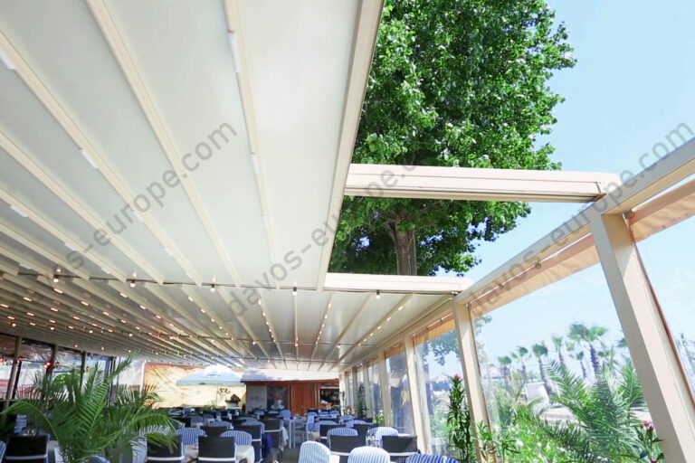 Pergola textila Davos de culoare crem montata pe terasa unui restaurant. Partial deschisa, vedere din interior.