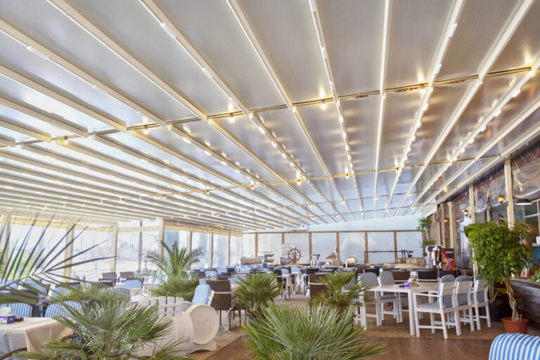 Pergola textila Davos de culoare crem montata pe terasa unui restaurant. Vedere din interior.